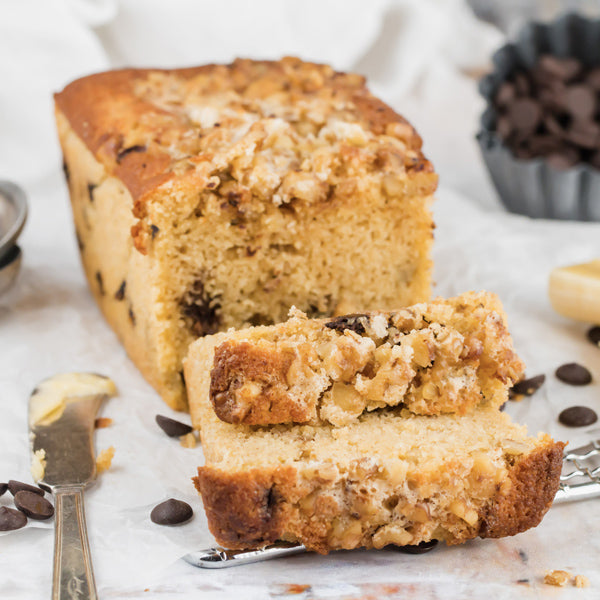 A loaf of chocolate chip keto banana bread, sliced and topped with nuts